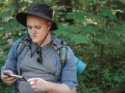 Top 10 Travel Apps You Need to Download Serious young man using tablet in forest during hiking tour