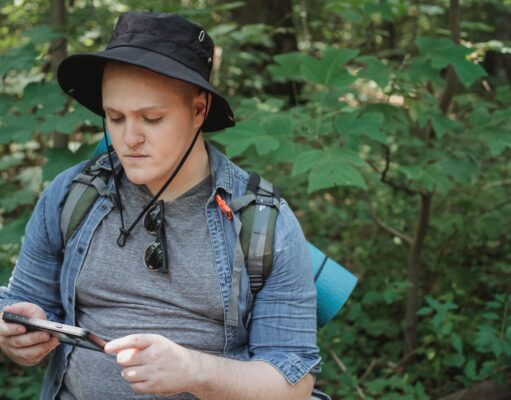 Top 10 Travel Apps You Need to Download Serious young man using tablet in forest during hiking tour