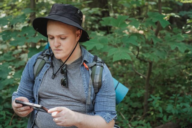 Photo by Kamaji Ogino Serious young man using tablet in forest during hiking tour