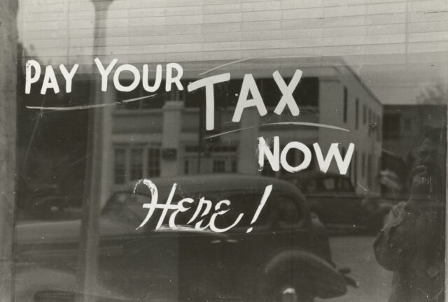 Photo by The New York Public Library a sign that says pay your tax now here