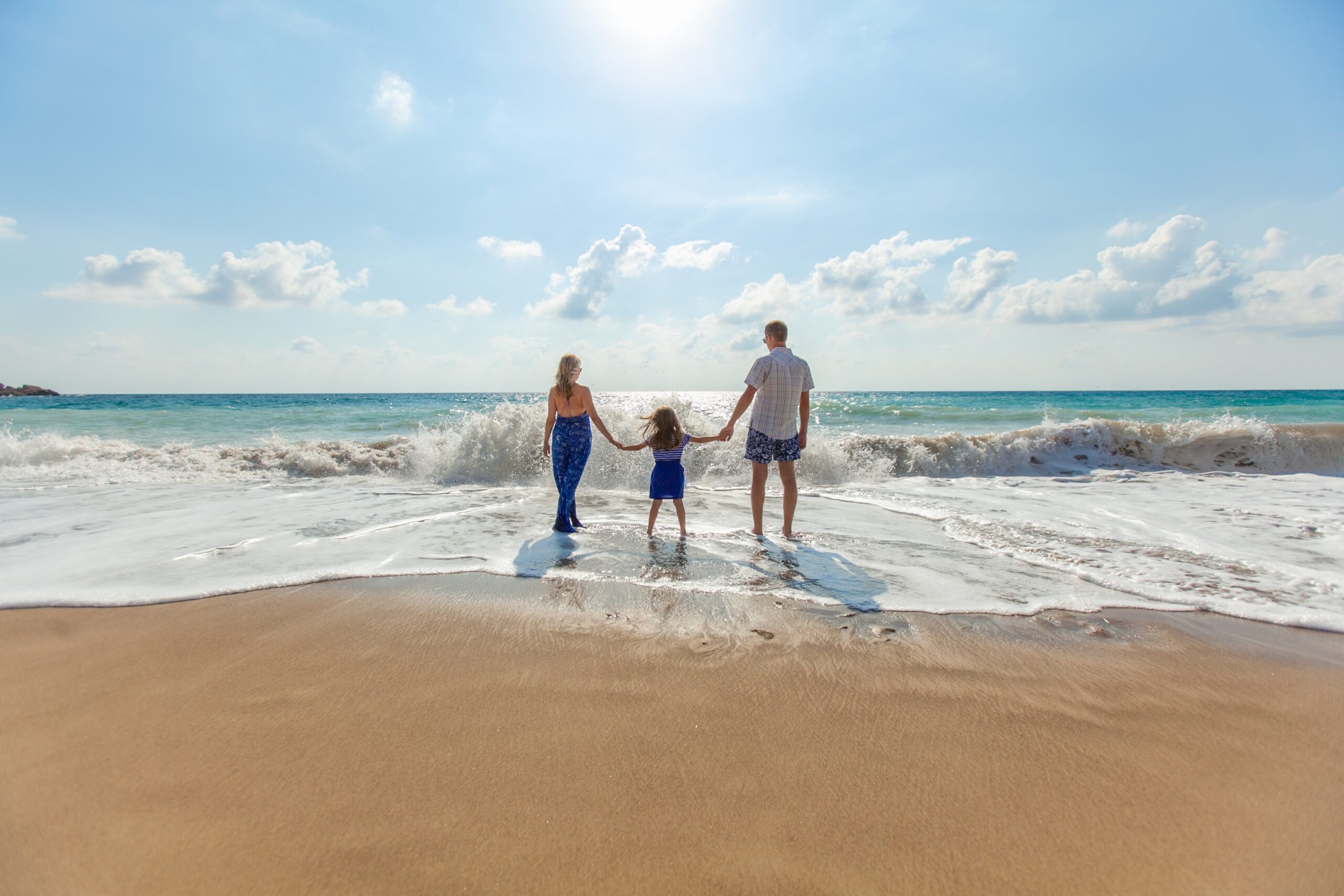 man, woman and child man, woman and child holding hands on seashore