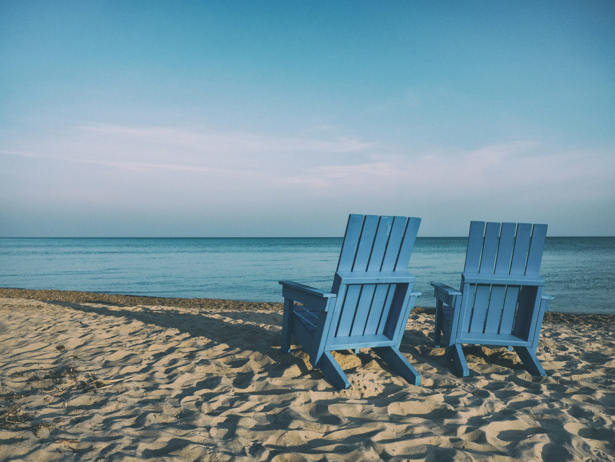 two blue beach chairs two blue beach chairs near body of water