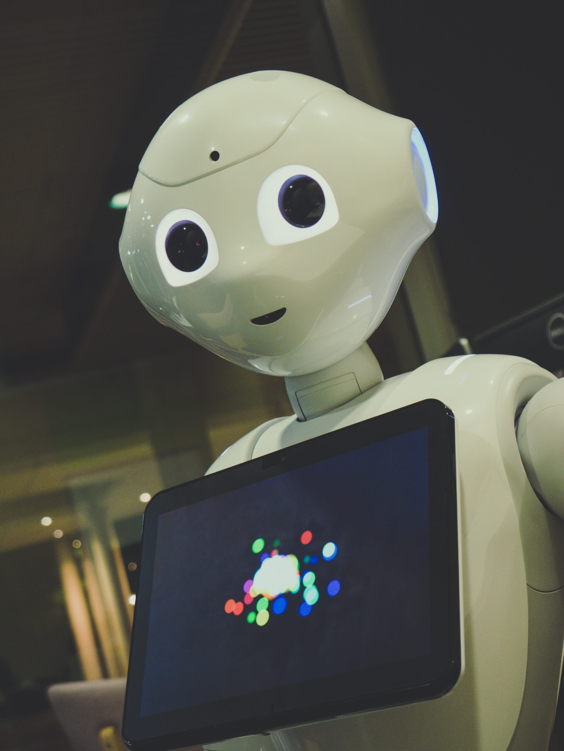 white robot toy holding white robot toy holding black tablet
