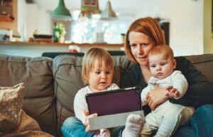 30 Flexible Stay-at-Home Jobs for Moms and Dads to Make Some Extra Cash two babies and woman sitting on sofa while holding baby and watching on tablet