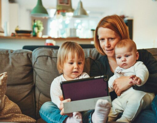 30 Flexible Stay-at-Home Jobs for Moms and Dads to Make Some Extra Cash two babies and woman sitting on sofa while holding baby and watching on tablet